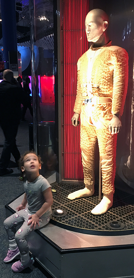 Aliyah posing in front of a Gold colored space suit